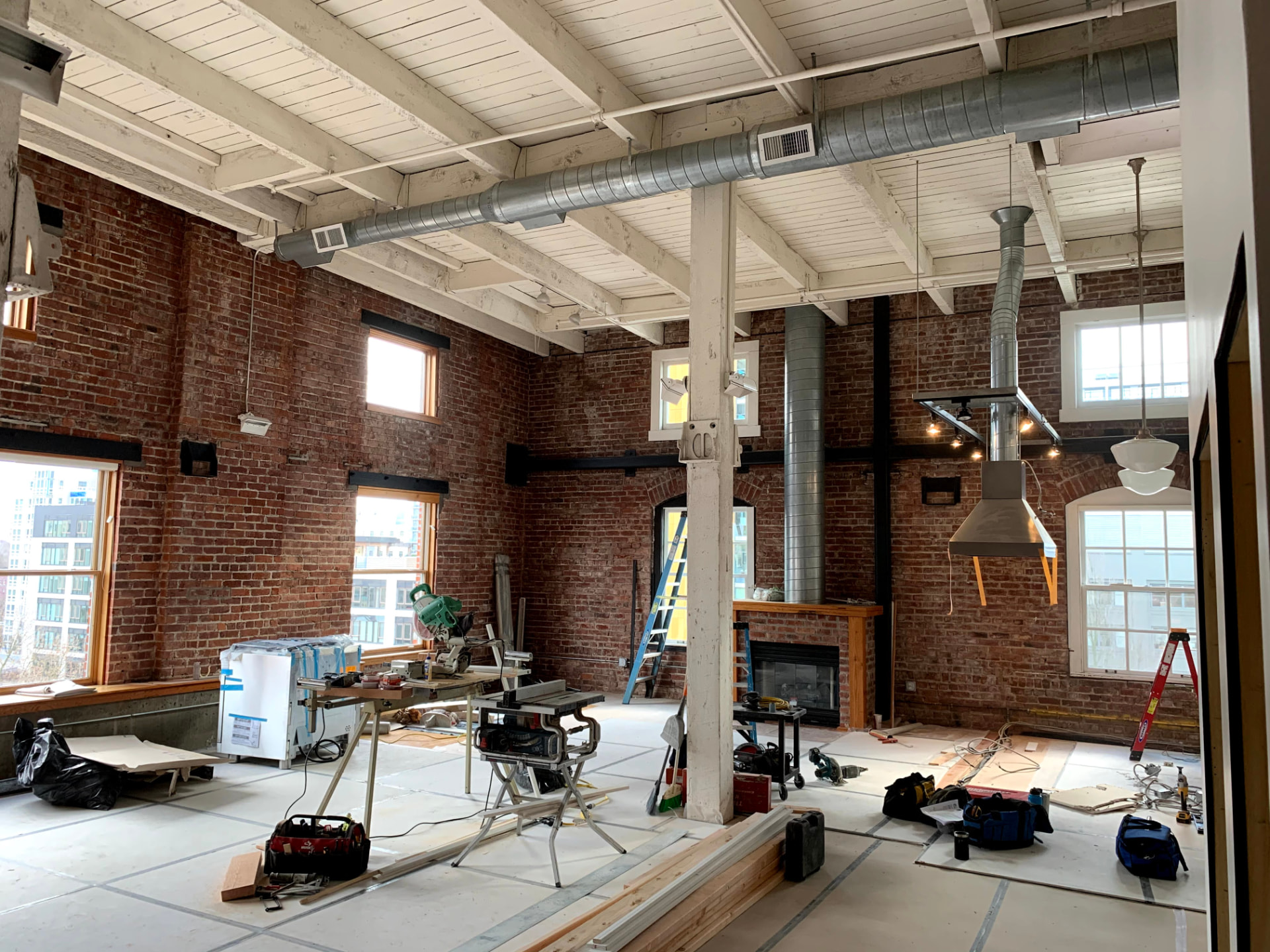 Historic brick building interior mid-remodel with exposed conduit and lighting
